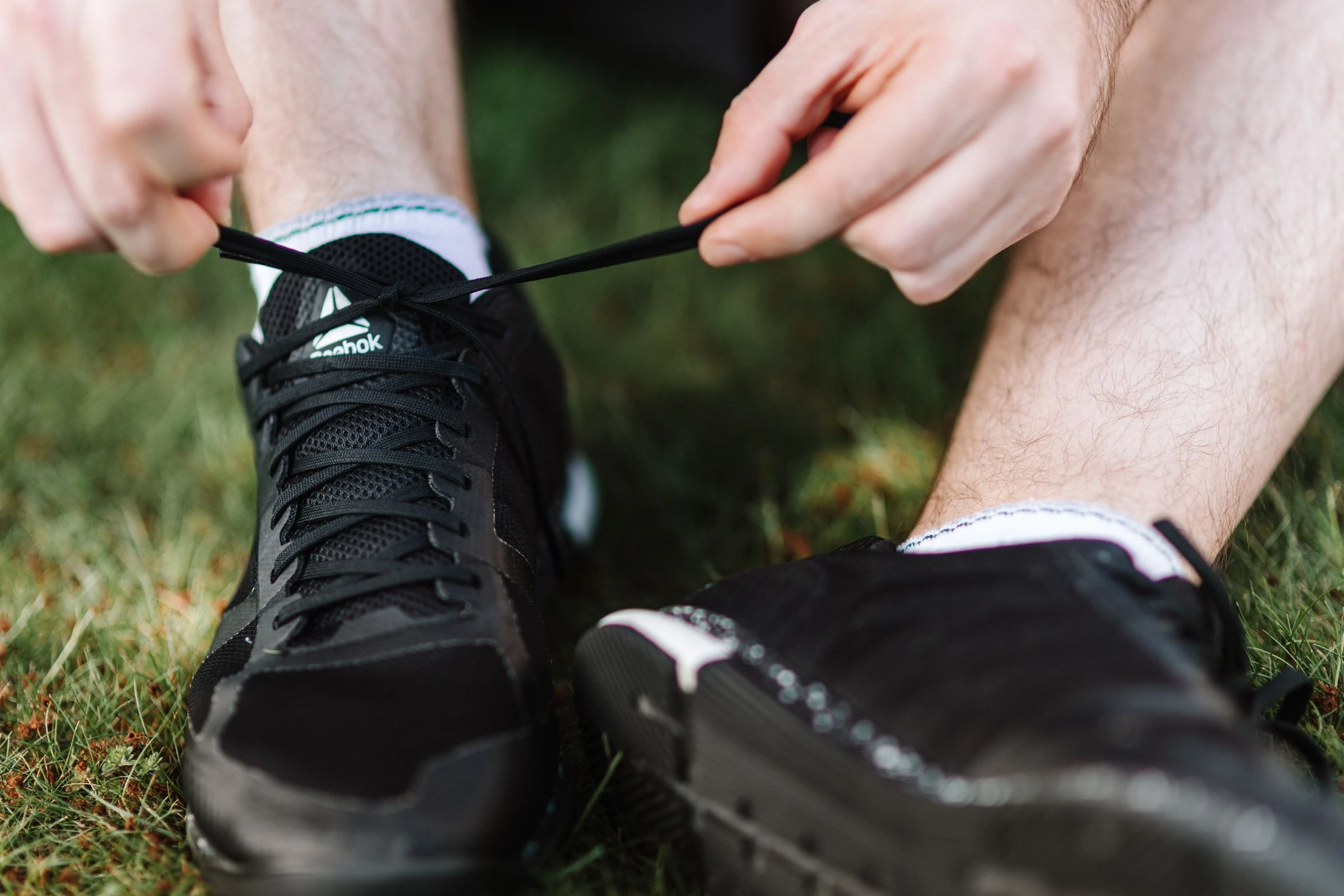 Quelqu'un lace ses chaussures de course, assis dans l'herbe